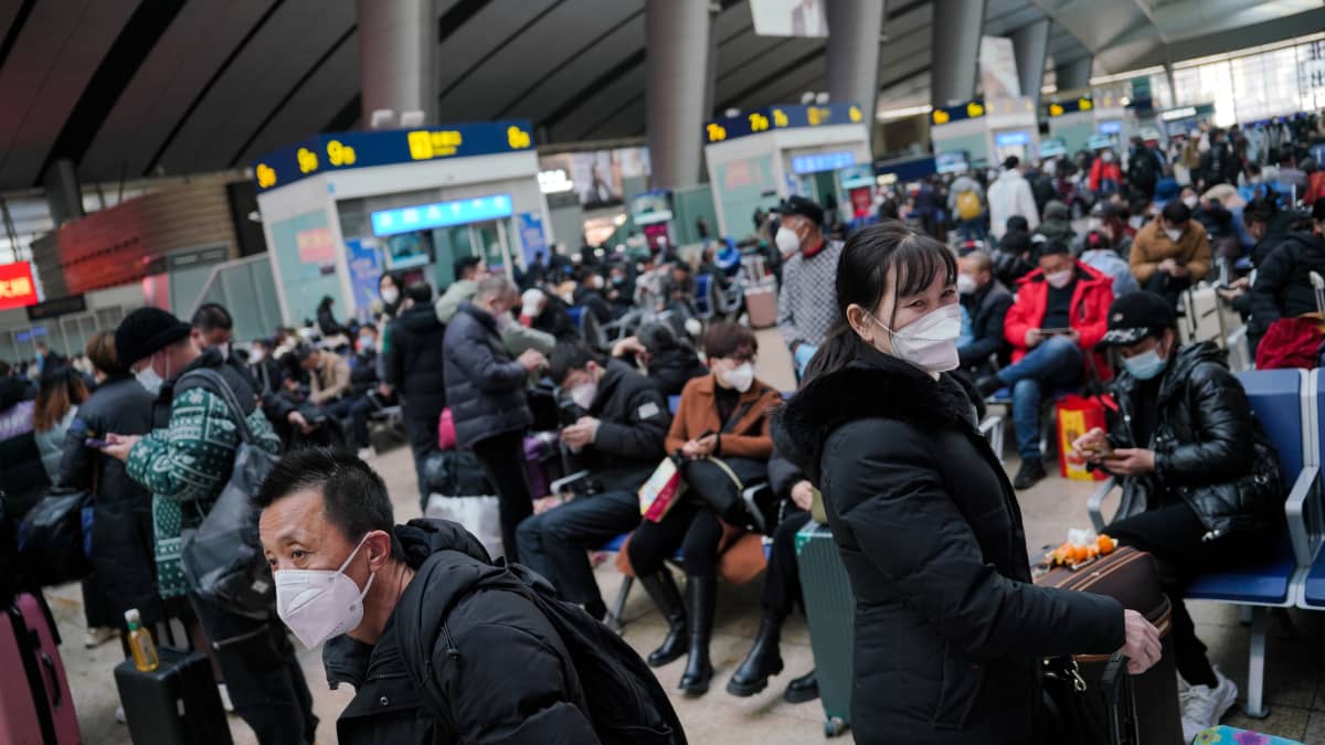 Matkustajat odottavat junaa kasvomaskit kasvoillaan Pekingin juna-asemalla uudenvuoden aattona.