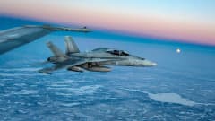 Suomen ilmavoimien Hornet-hävittäjät lennolla korkealla ilmassa talvisaikaan.