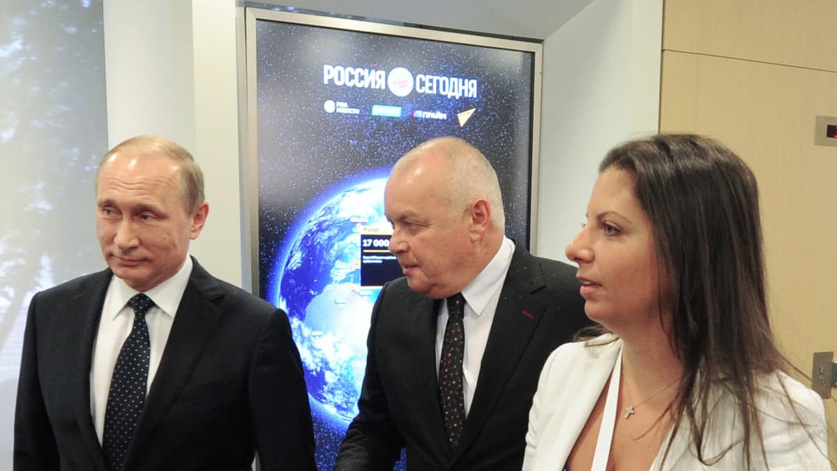 Vladimir Putin kävelee Venäjän valtion kansainvälisen RT-uutiskanavan päätoimittajan kanssa.