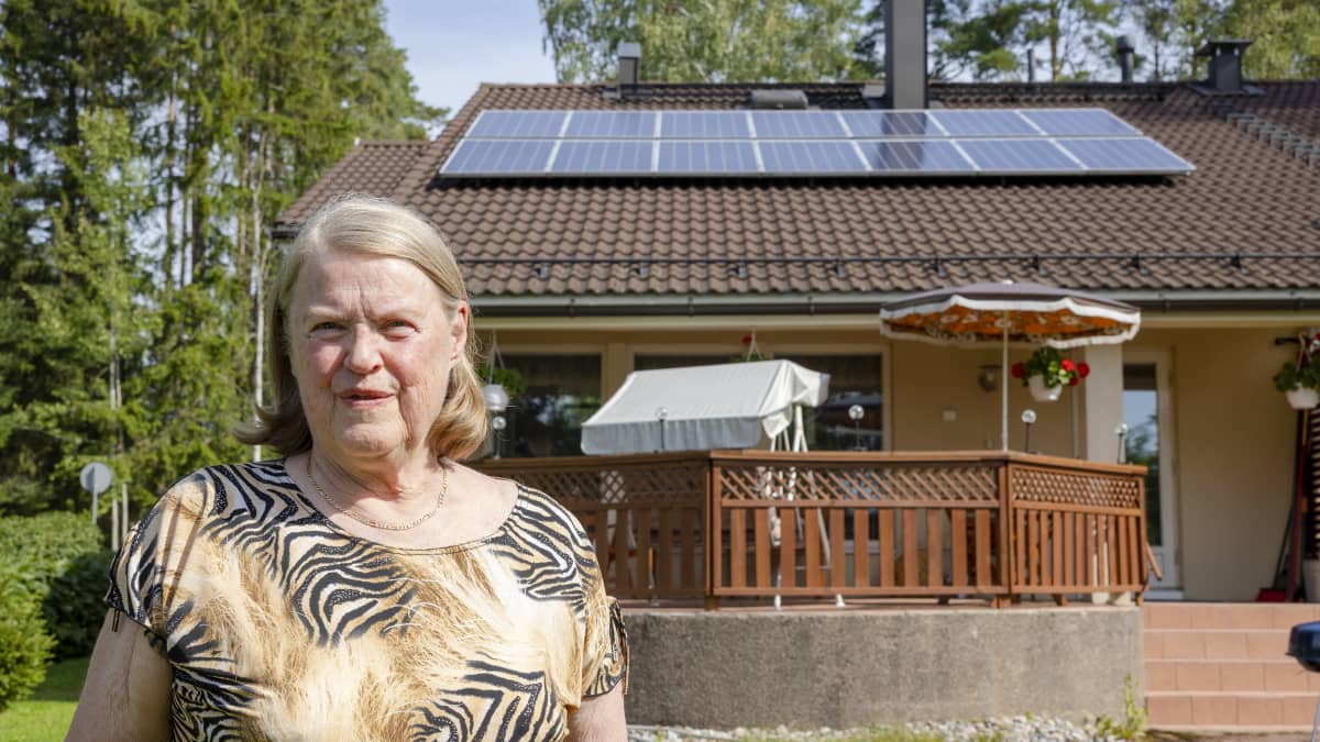 Nainen seisoo talon takapihalla. Taustalla näkyy aurinkopaneelit talon katolla.