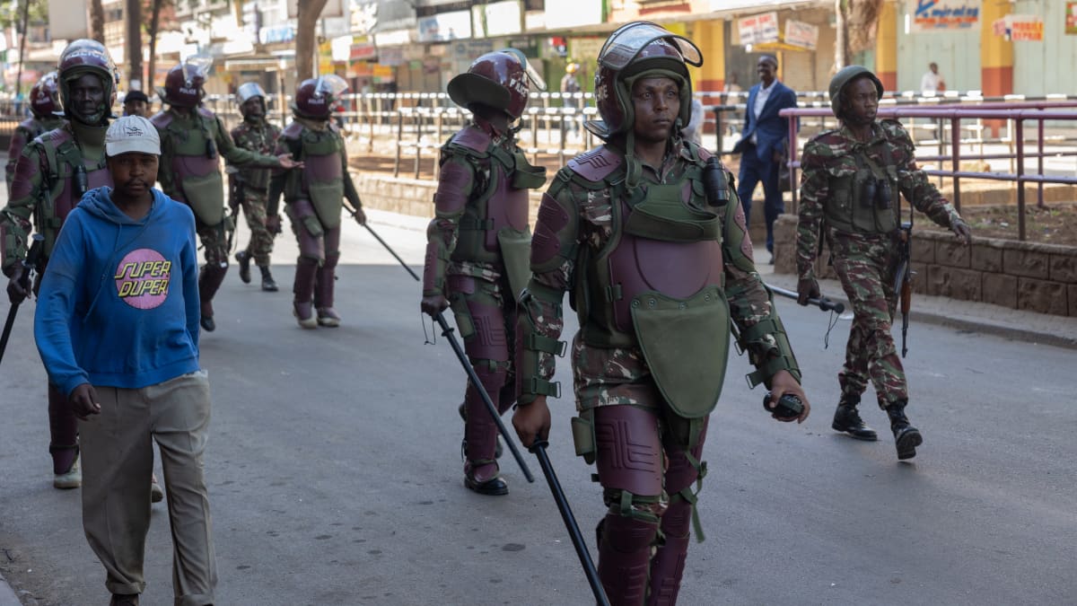Kenialaiset poliisit marssivat Nairobin kadulla mellakkavarusteissa. 