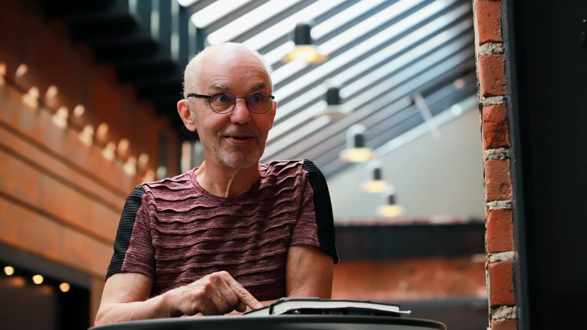 Olli Tiuraniemi seisoo aulassa, pöydän ääressä.