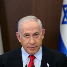 Netanjahun kasvot, taustalla Israelin liput.