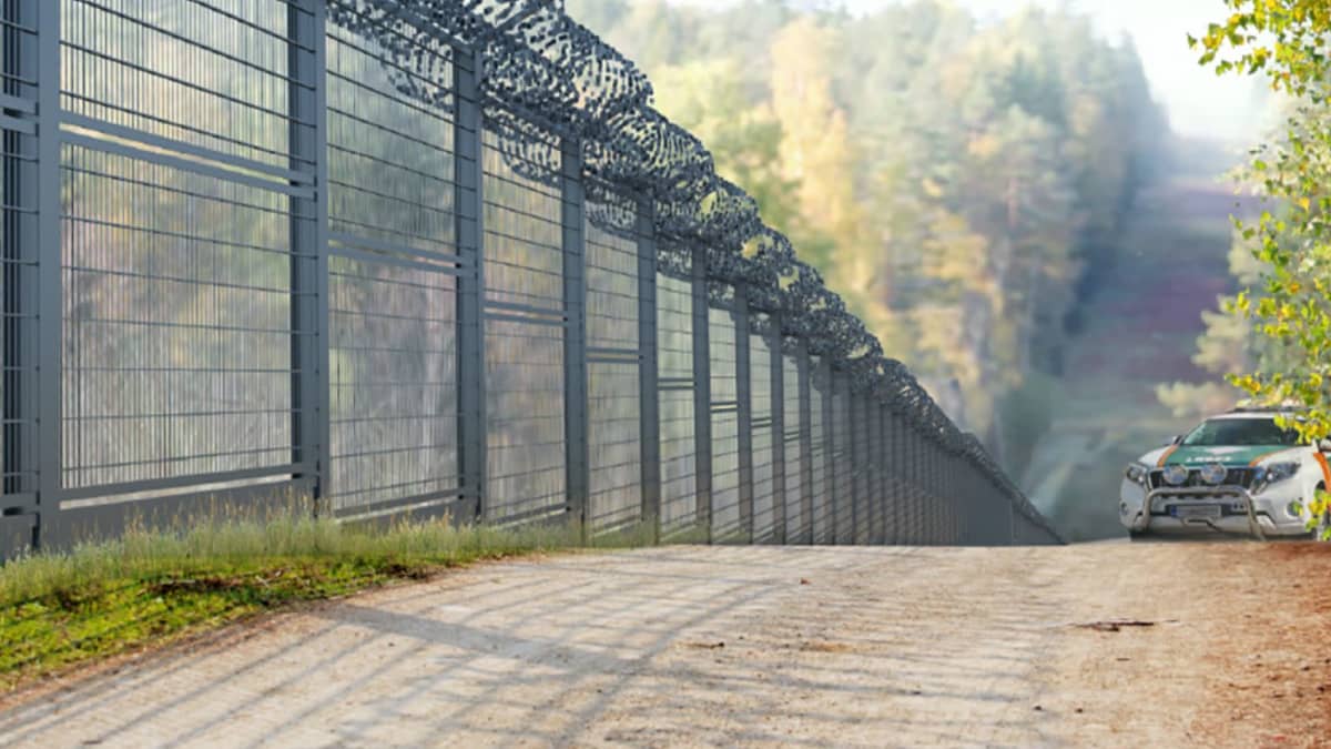 Kuvassa rautainen korkea aita, taustalla tie.