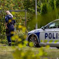 Photo shows a police officer investigating a forest scene.