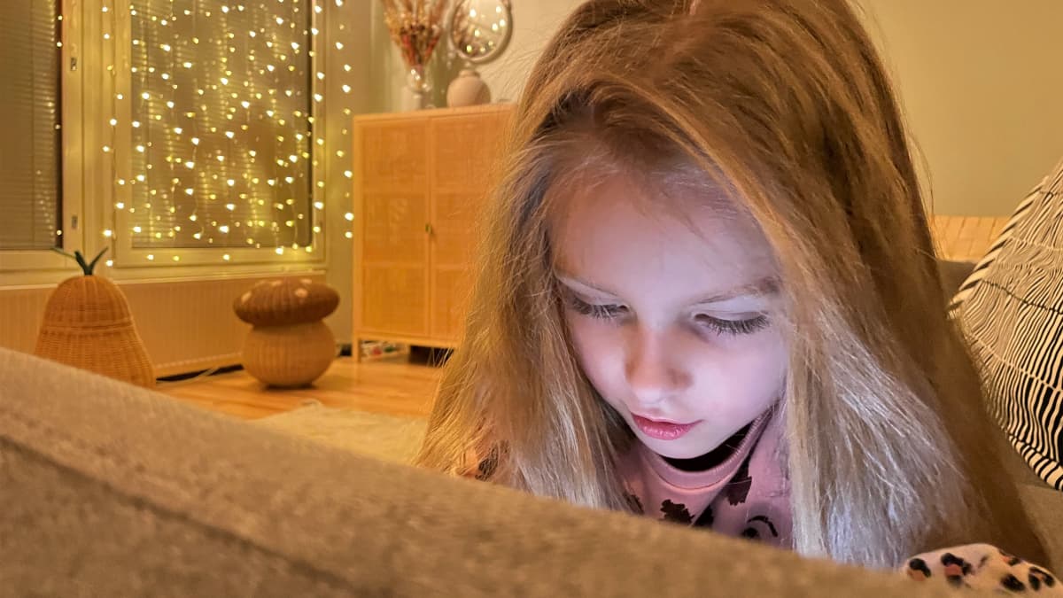 Laihialainen 7-vuotias Matilda Knuutti makaa sohvalla ja katsoo puhelinta.