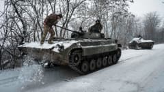 Sotilas potkii lunta panssarivaunun kannen päältä.