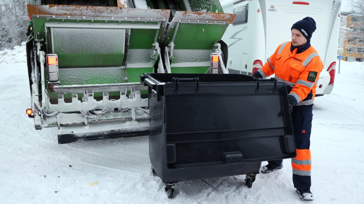 Jäteauton kuljettaja Pasi Jäntti tyhjentää roska-astioita jäteautoon.