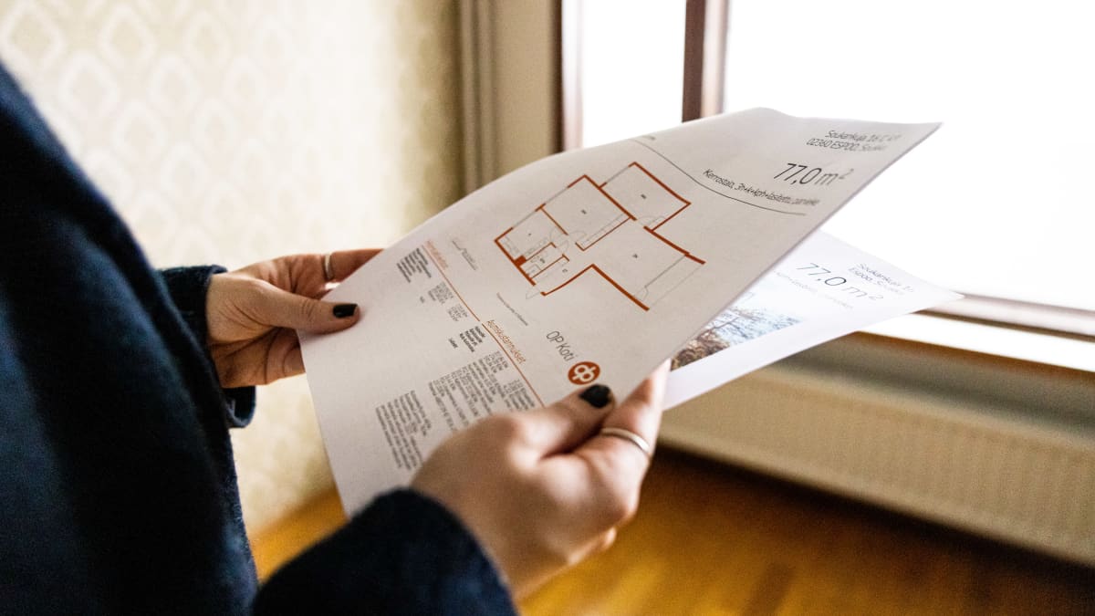 Hands holding a bundle of paper, featuring an apartment floor plan illustration.