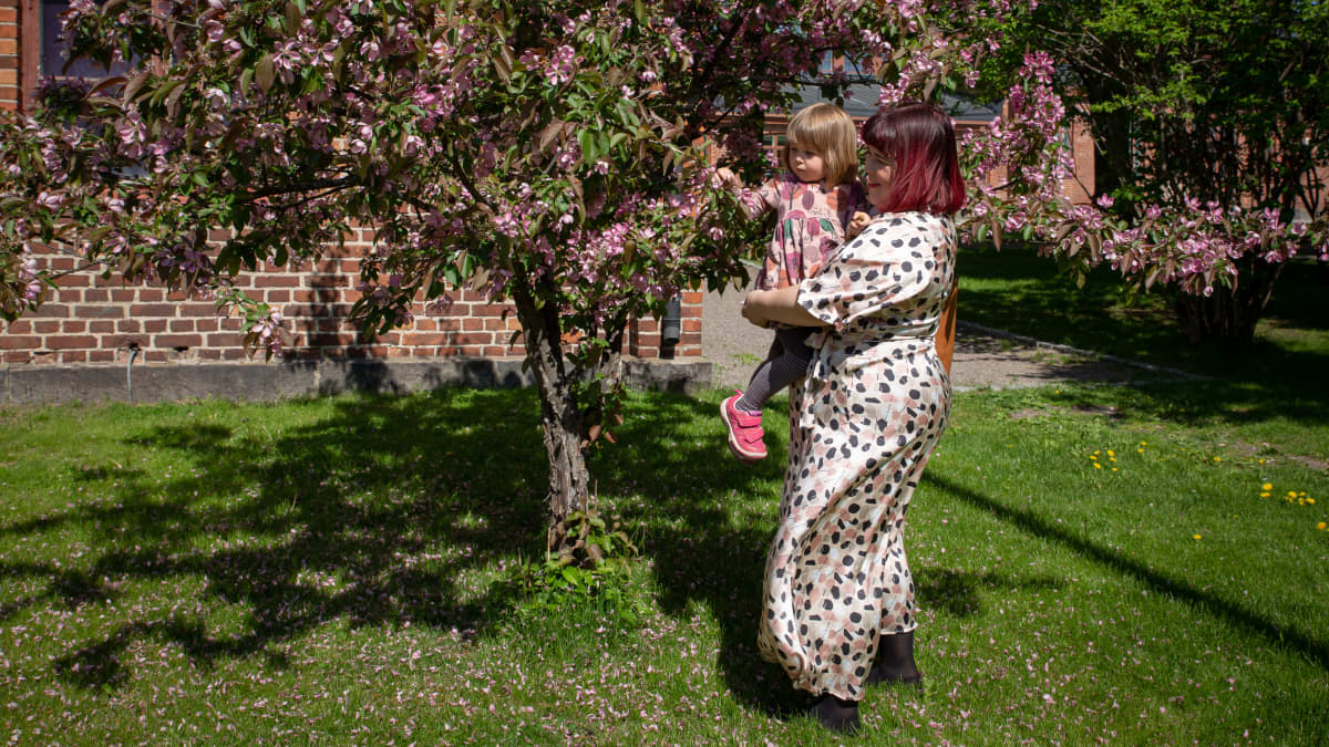 Tiia Trogen ihailee puun kukkia lapsensa Sofian kanssa.