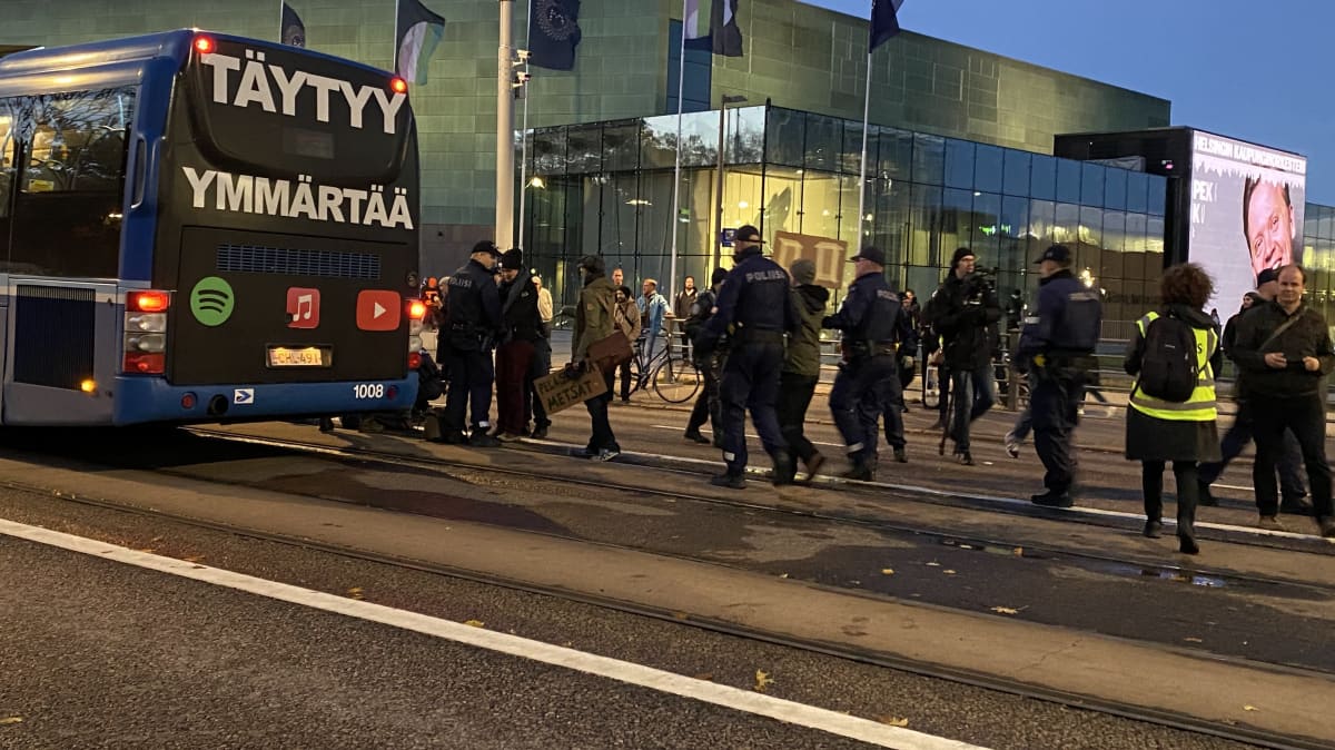 poliisi ohjaa mielenosoittajia bussiin