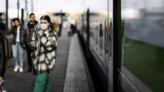 Kuvassa kasvomaskia käyttävä nainen astuu ulos junasta Helsingissä lokakuussa 2020.