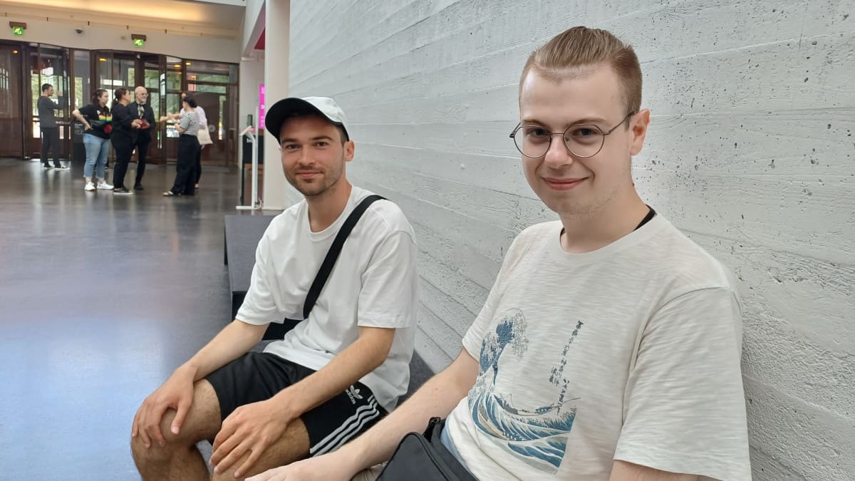 Kaksi nuorta miestä istumassa Kiasman aulassa.