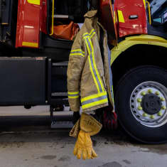 Kymenlaakson pelastuslaitoksen paloauto ja sen ovessa riippuva palomiehen takki.
