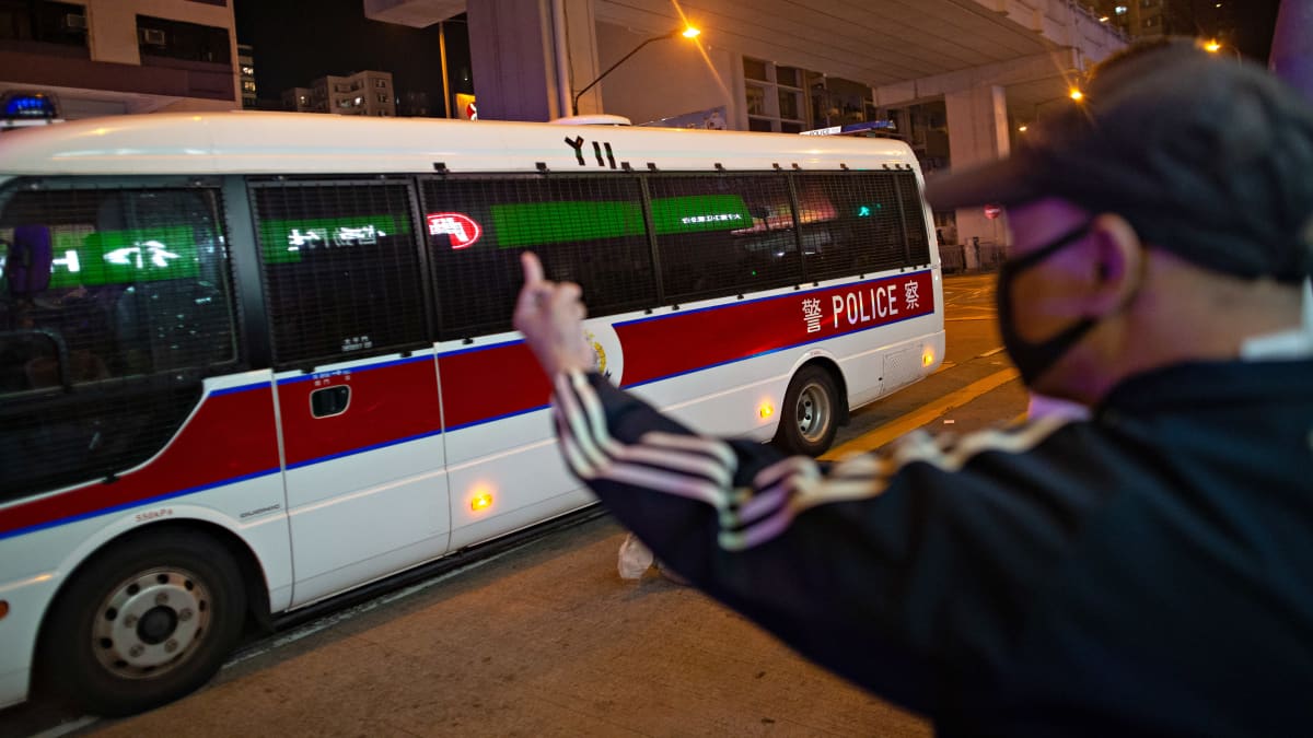 Mies reagoi käsimerkeillään ohi ajavaan poliisibussiin Hongkongissa 30. marraskuuta 2019.