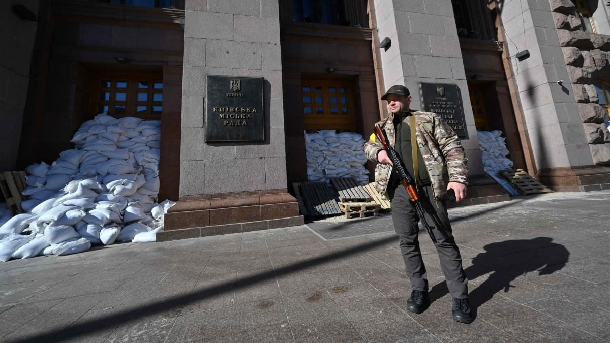 Ukrainan aluepuolustusvoimien taistelija seisoo vartioimassa Kiovan kaupungintalon edessä hiekkasäkeillä suojatun ikkunoiden ja ovien edessä Kiovan keskustassa 28.2.2022.