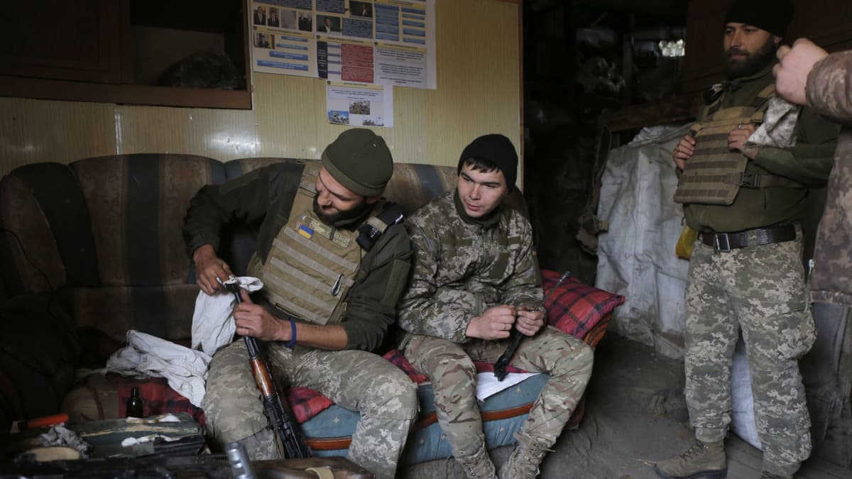 Ukrainalaisia sotilaita istuu sohvalla jossakin kasarmissa tai bunkerissa. Sotilas puhdistaa rynnäkkökivääriä. 