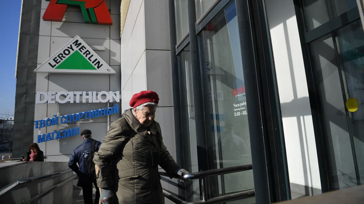Iäkäs nainen kävelemässä sisään kauppakeskukseen Moskovassa.