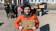 Opettaja Aleksej Fedorov Kauppatorilla, taustalla oppilaat ja vanhemmat mielenosoituksessa. Fedorovin kyltissä lukee "Palkanmaksut kuntoon", oppilaat ovat theneet kyltin hänelle..