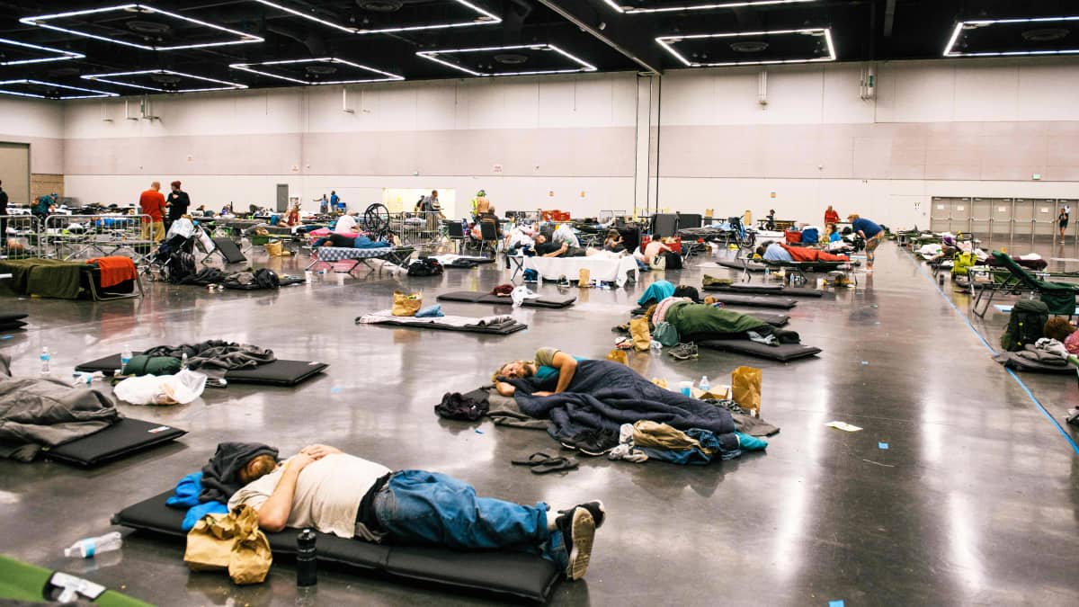 Ihmiset makaavat konferenssikeskuksen lattialla.