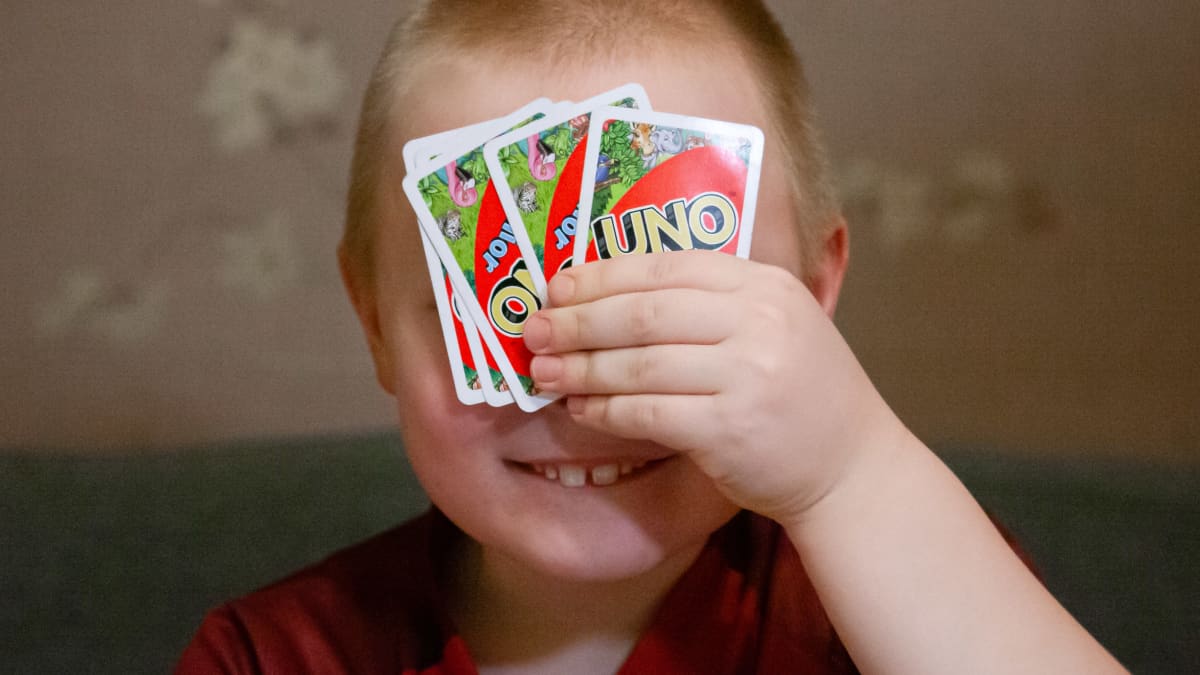 Onni Laine pitelee Uno-pelikortteja kasvojensa edessä.