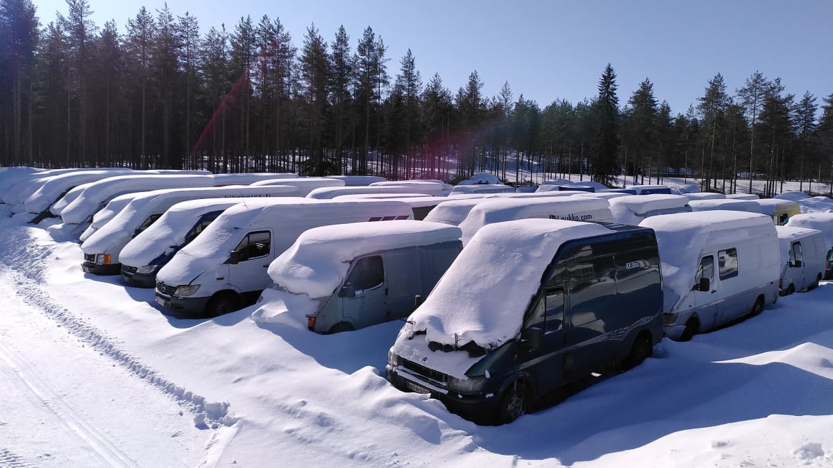Useita pakettiautoja lumen peittäminä.