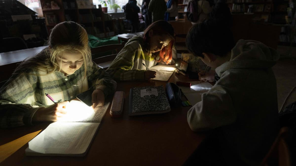 Lapset opiskelevat taskulampun valossa.