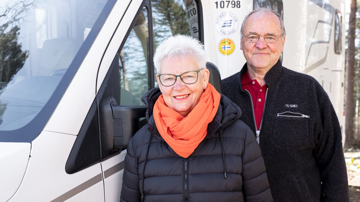 Pentti ja Pirkko Äijö poseeraavat matkailuautonsa vieressä.