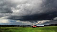 Photo of dark clouds over a field and farm.