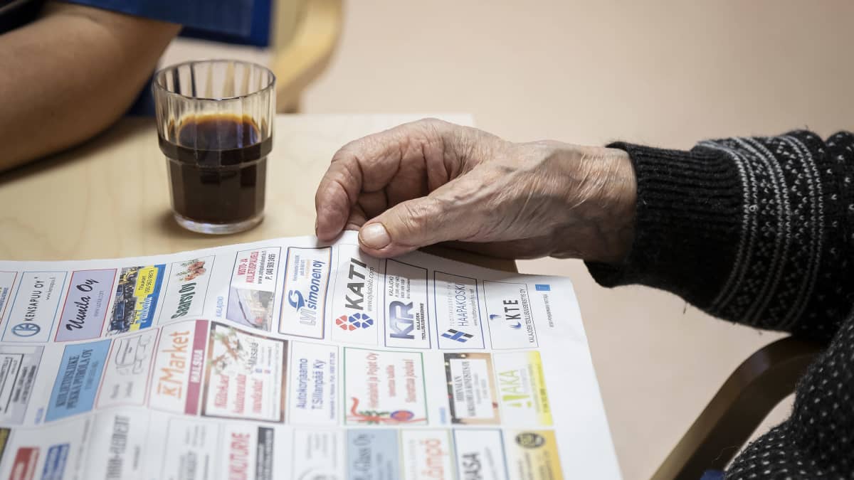 Vanhus selailee lehteä palvelukeskuksessa. 