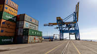 Stacks of shipping containers and a large crane on a shipping pier. 