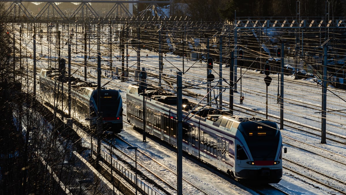 Kaksi junaa kovassa talvisessa valossa ajavat leveää ratapihaa Helsingin päärautatieaseman ja Mall of Triplan välisellä osuudella.