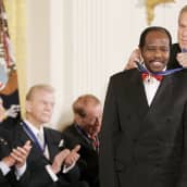 George W. Bush ripustaa Yhdysvaltain presidentin vapaudenmitalin Paul Rusesabaginan kaulaan.