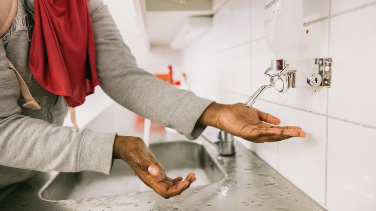 Nuori henkilö pesee käsiään.