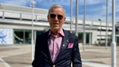 Åland businessman Anders Wiklöf in a blue blazer with pink shirt and pocket square, wearing sunglasses, in the sunshine outside the Åland parliament building.