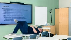 Tommi Kinnunen makaa pulpettien päällä koululuokassa.