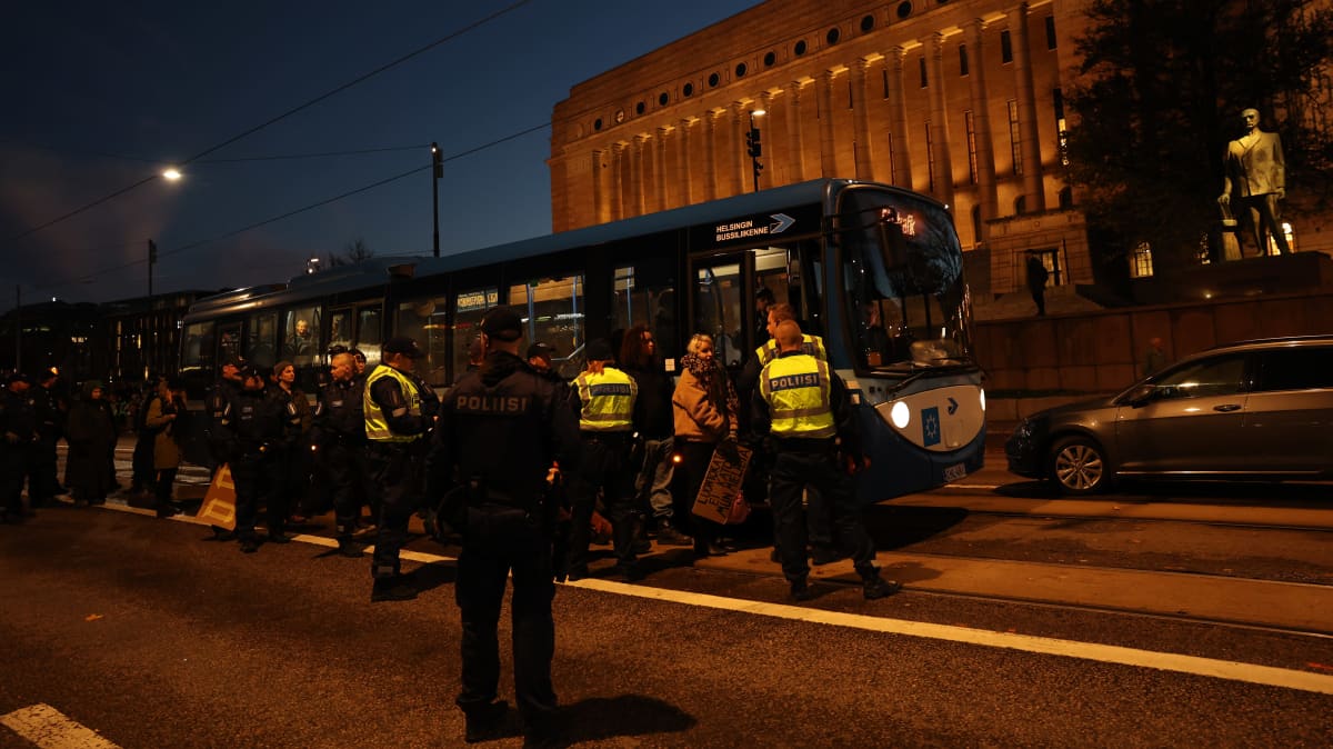 poliisi ohjaa mielenosoittajan linja-autoon