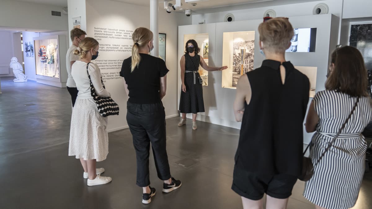 Museolehtori Jonna Kokkola esittelee Helsingin Olympialaisten Olympiasoihtua Urheilumuseon opastetulla yleisökierroksella. 