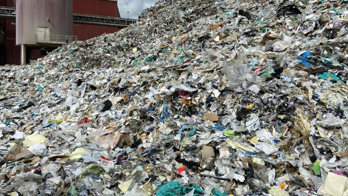 Kuvassa on Kaipolan entisen paperitehtaan pihamaalla seisova iso kasa silputtua muovia. Kierrätysmuovi on menossa tehtaan voimalan kattilaan poltettavaksi