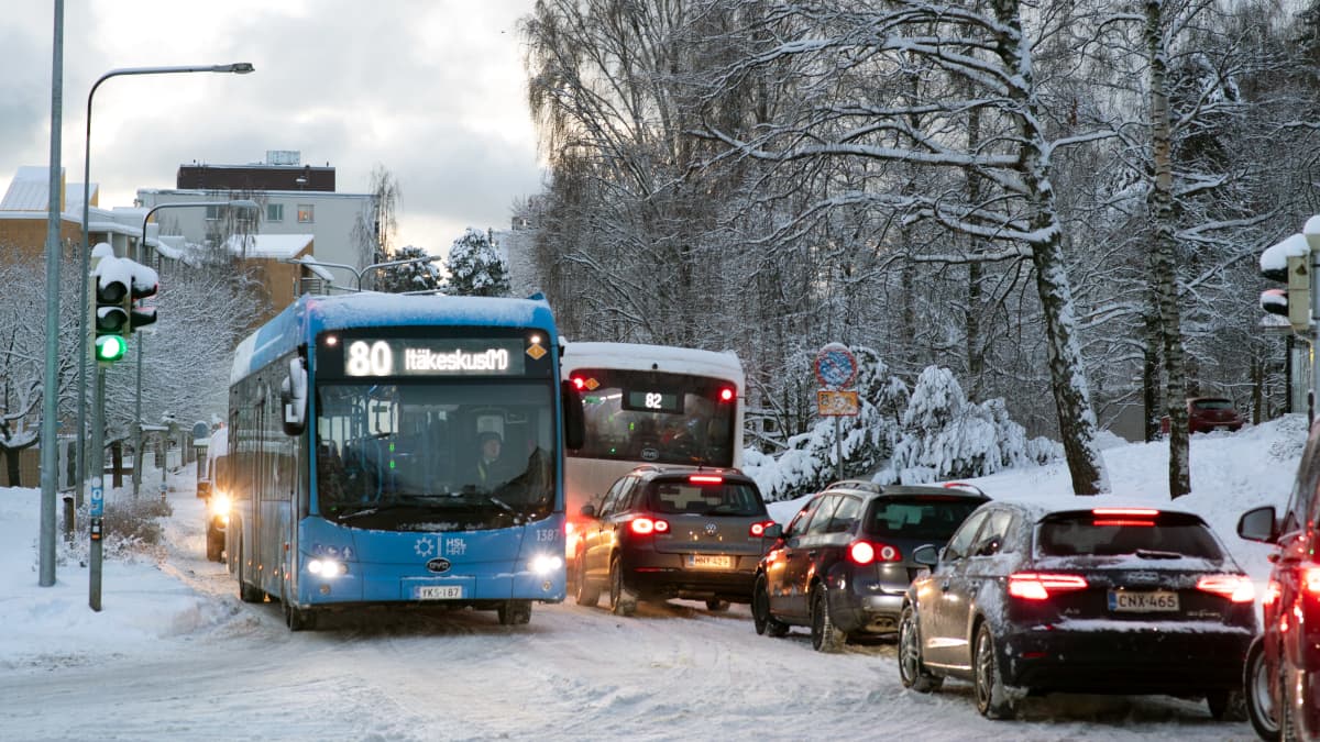 Busseja ja autoja lumisessa katujen risteyksessä.