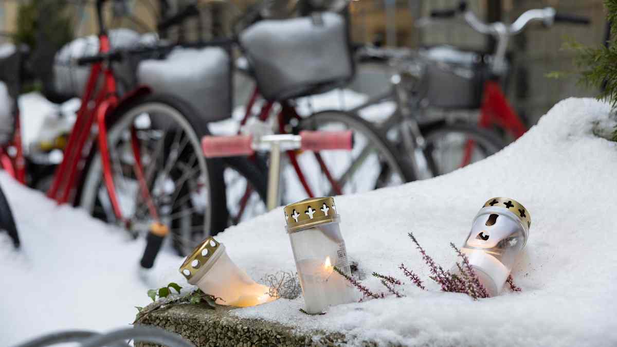 Hautakynttilöitä lumessa Ullanlinnan surmapaikan edessä 18. joulukuuta. Taustalla luminen piha ja polkupyöriä.