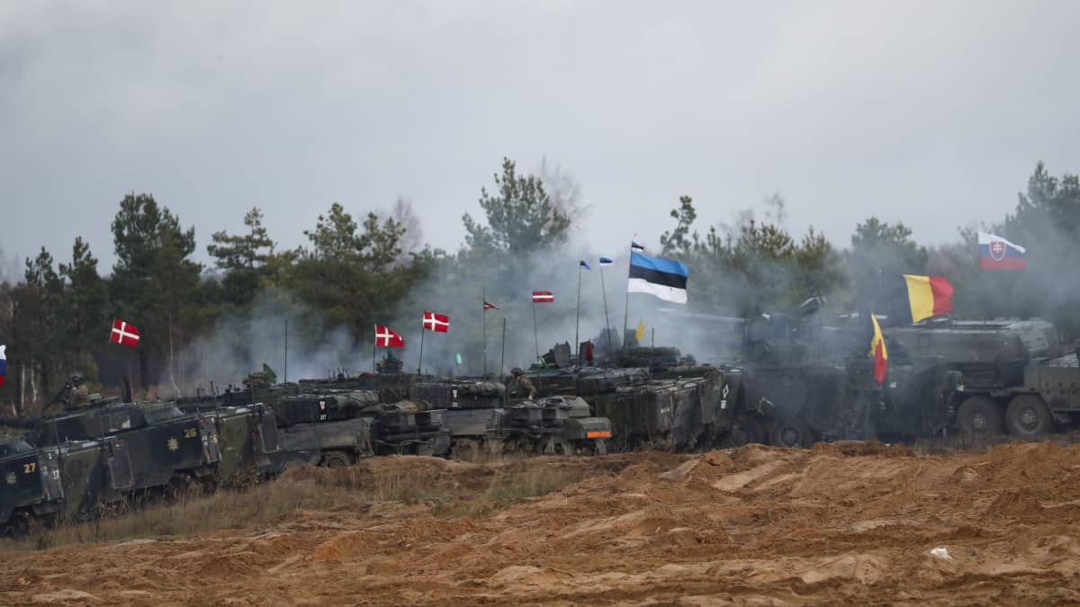 Panssaroituja ajoeuvoja, joissa liehuu Nato-maiden lippuja. Keskimmäisenä on Viron lippu.