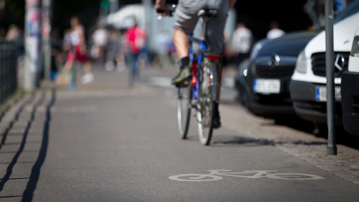 Anonyymi mies pyöräilee pyöräkaistalla kaupungissa kesällä.