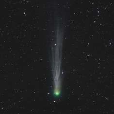 Tähtitaivaalla komeetta, vihreänä johtava valopallo, jonka perässä himmeämpi valo pyrstö.