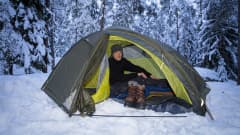 Mies majoittuu teltassa talvella. 
