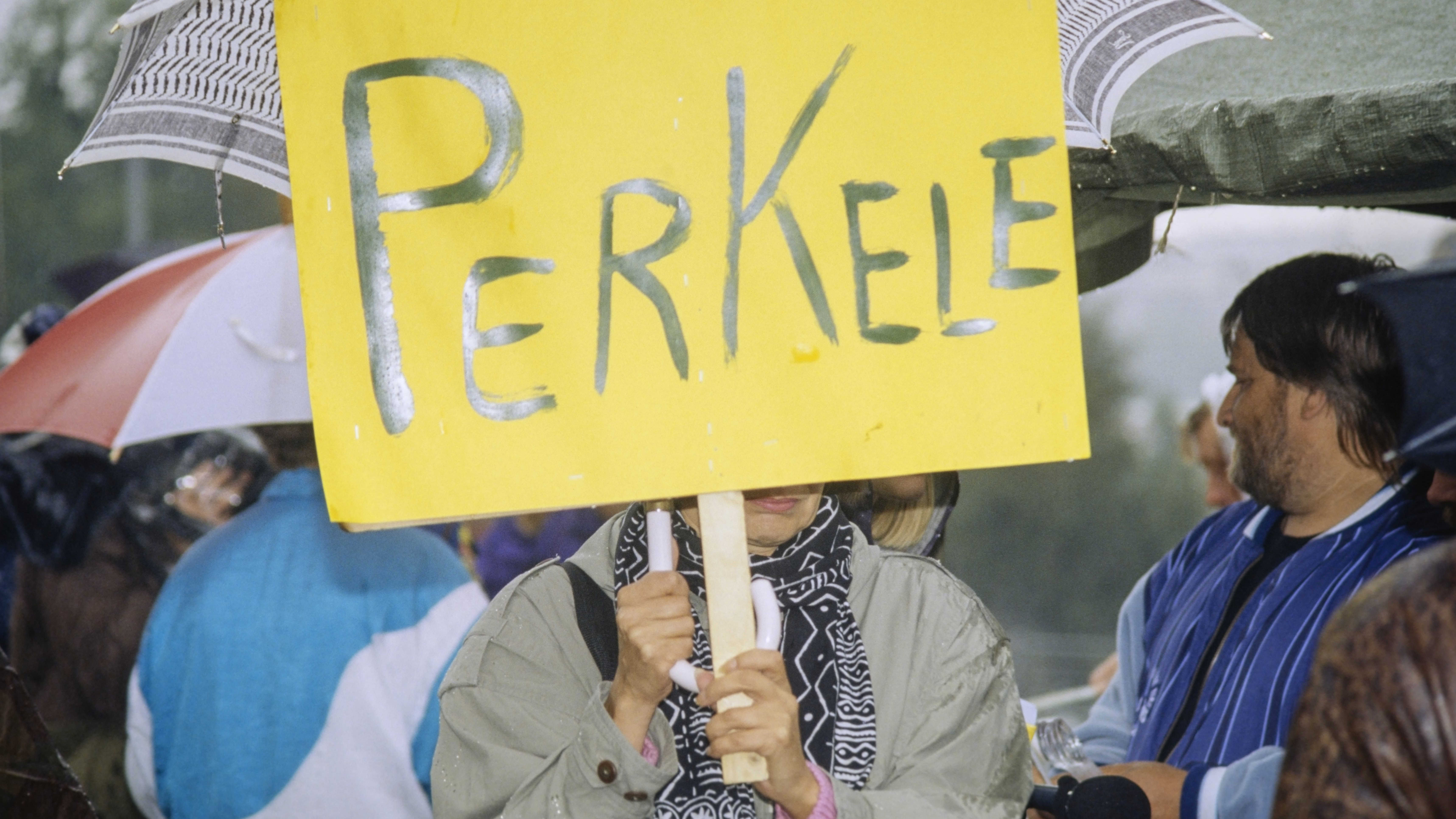 Työttömien mielenosoitus Helsingissä, marssijoita iskulauseineen ja banderolleineen eduskuntatalon edessä, henkilö pitelee kylttiä, jossa lukee "Perkele", 2. syyskuuta 1993.