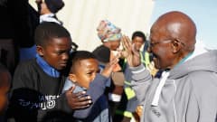 Desmond Tutu tervehtii lapsia.