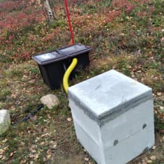 Valkoinen ja musta mittauslaatikko maassa. 