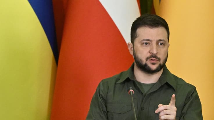 Ukrainan presidentti puhuu taustallaan lippuja.