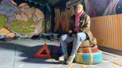Nuori nainen istuu graffitein koristellussa huoneessa rengaspinon päällä.